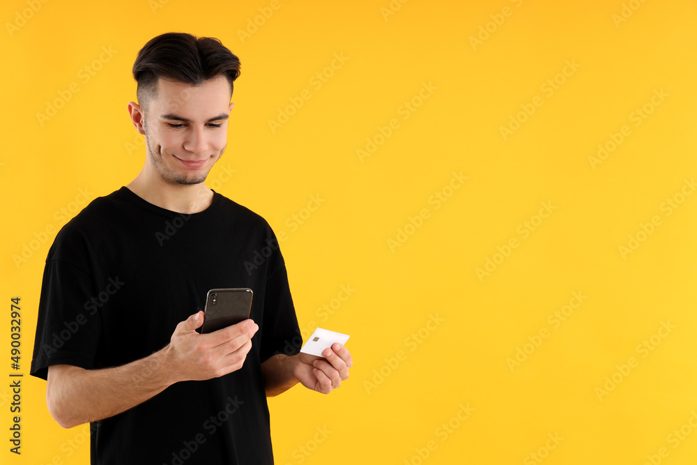 Guy with phone and credit card on yellow background