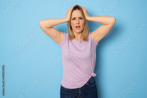 Portrait of amazed young woman over blue background © Danko