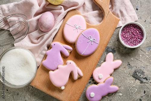 Photography Wooden board with tasty Easter cookies and painted egg on grey background
