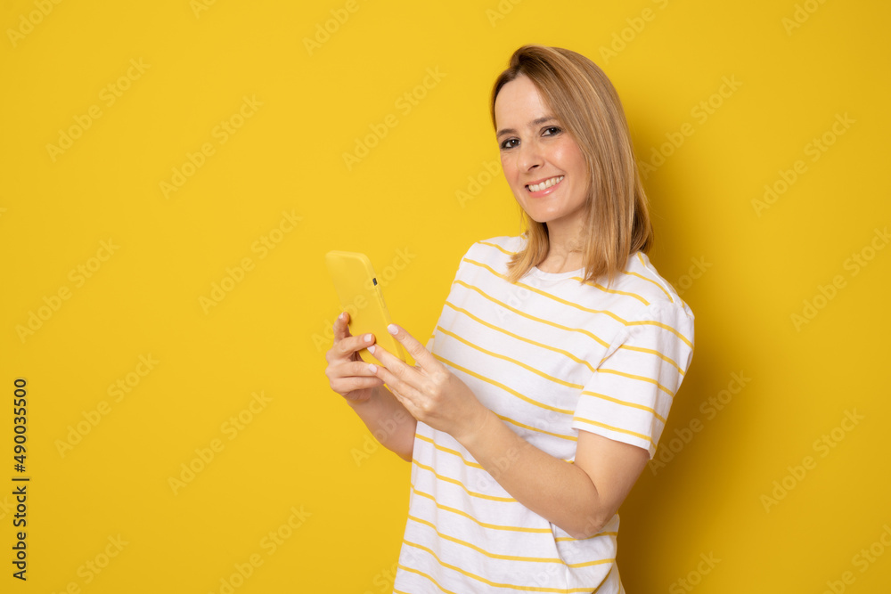 Portrait of a beautiful young woman using smartphone isolated over yellow background Portrait of a beautiful young woman using smartphone isolated over yellow background