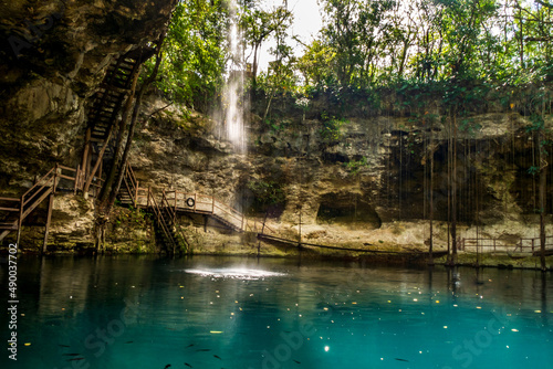 Cenote Ek Balam X'Canche near Valladolid, Yucatan, Mexico. Blue water with little waterfall 