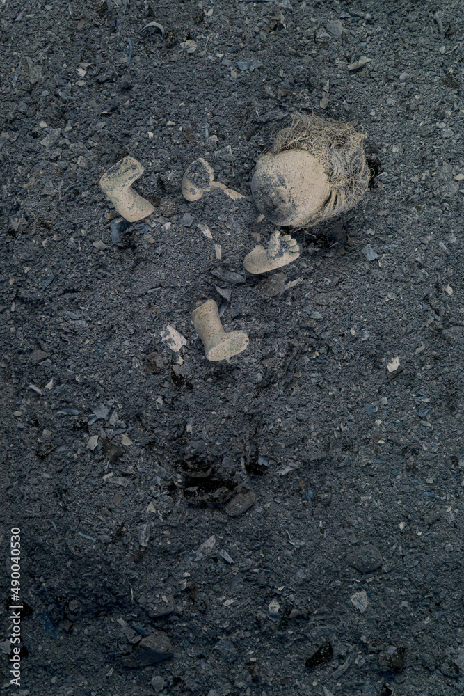 Abandoned doll in a pile of grey ashes. Violence against the Ukrainian people concept. War, devastation and ruins in Ukraine, 2022. Abandoned doll in a pile of grey ashes. Violence against the Ukrainian people concept. War, devastation and ruins in Ukraine, 2022.