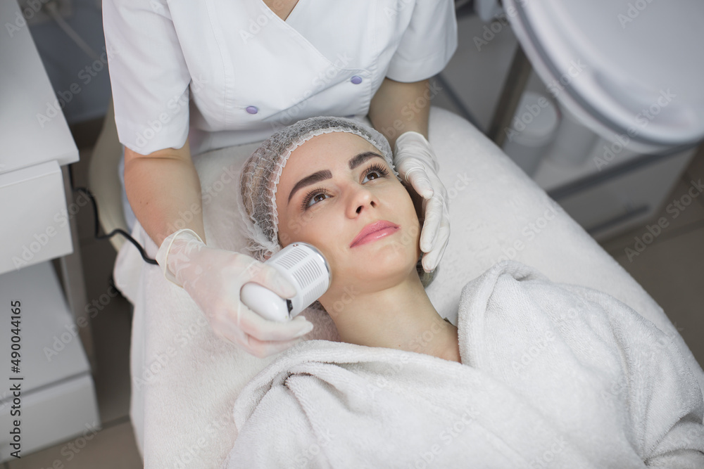 Cosmetology. Beautiful Woman Receiving Facial Skin Ultrasound Cavitation. Closeup Of Female Face Receiving Anti-Aging Cosmetics Using Ultrasound Cavitation Machine. Body Care