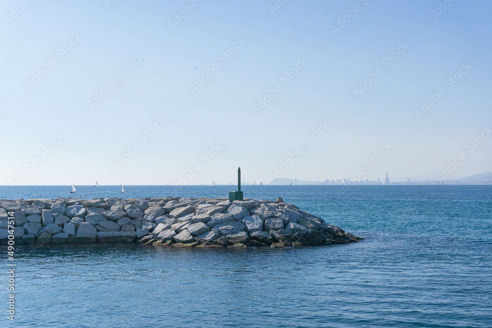 Rock jetty and small lighthouse in the seaport of Premia de Mar - obrazy, fototapety, plakaty 
