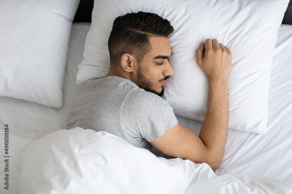 Young Arab Man Sleeping In Comfortable Bed At Home, Top View Young Arab Man Sleeping In Comfortable Bed At Home, Top View