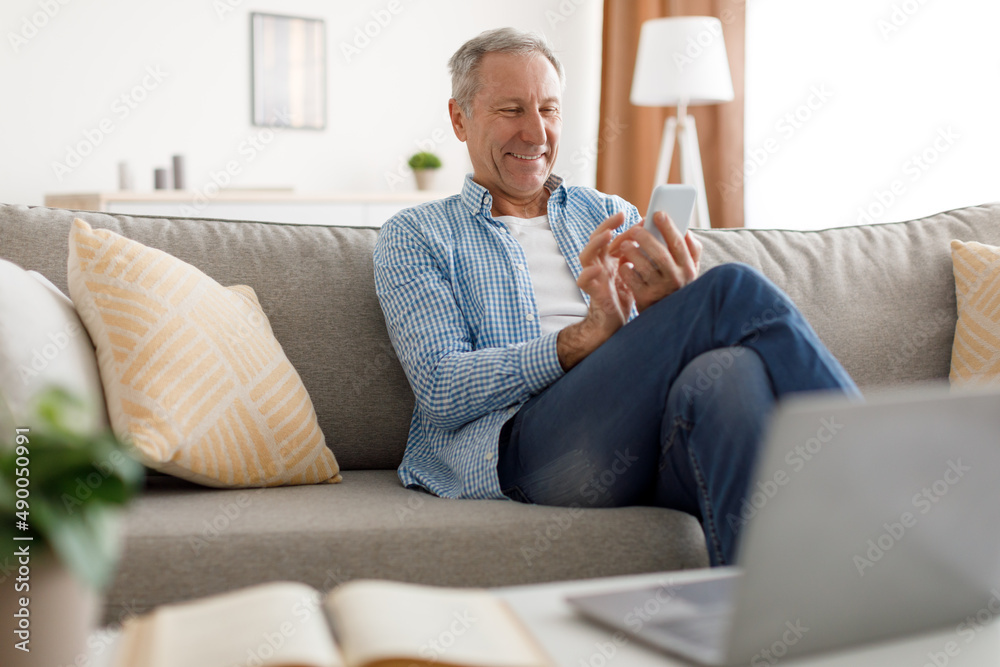 Portrait of smiling mature man using smart phone at home Portrait of smiling mature man using smart phone at home