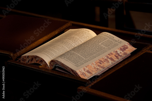 An open book of the Talmud, the central text of Rabbinic Judaism and the primary source of Jewish religious law, lies on a desk in a Yeshiva study hall. photo