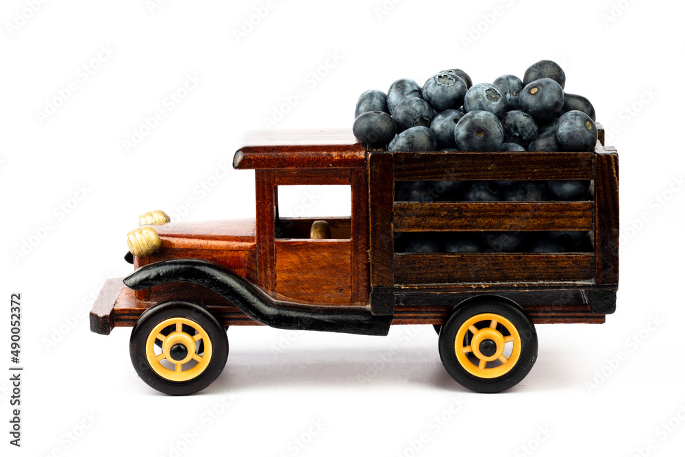 Fototapeta premium Ripe blueberry in wooden toy truck on white background.