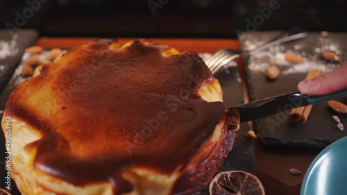 hand slicing crusty classic basque san sebastian cheesecake with cream cheese photo