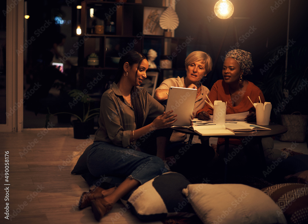 This app will help us complete the deadline. Shot of a group of businesswomen working together on a digital tablet in an office at night. This app will help us complete the deadline. Shot of a group of businesswomen working together on a digital tablet in an office at night.