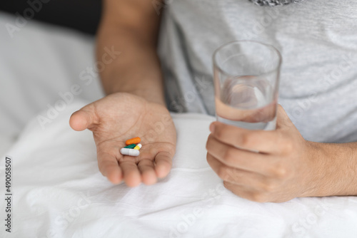 Unrecognizable Male Holding Glass Of Water And Pile Of Pills