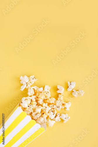 Spilled popcorn and paper bucket on background. Movie night concept. Copy space for text