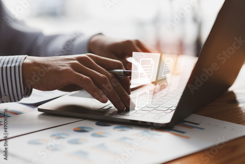 Businessman working on a laptop computer to document management online documentation database digital file storage system software records keeping database technology file access doc sharing. photo