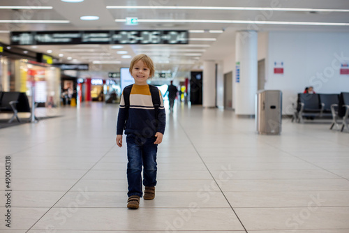 Cute baby boy waiting boarding to flight in airport transit hall near departure gate. Active family lifestyle travel by air with children