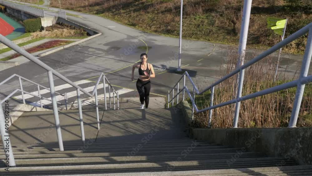 Athletic young woman running up steps Slow motion wide shot