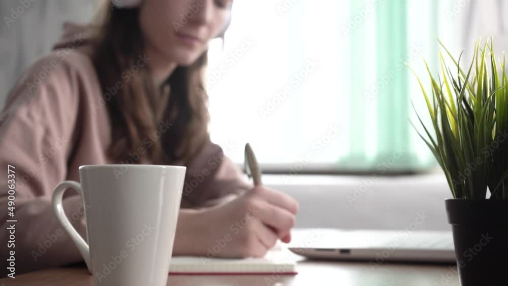 A girl takes notes in a notebook from her laptop. Distance learning