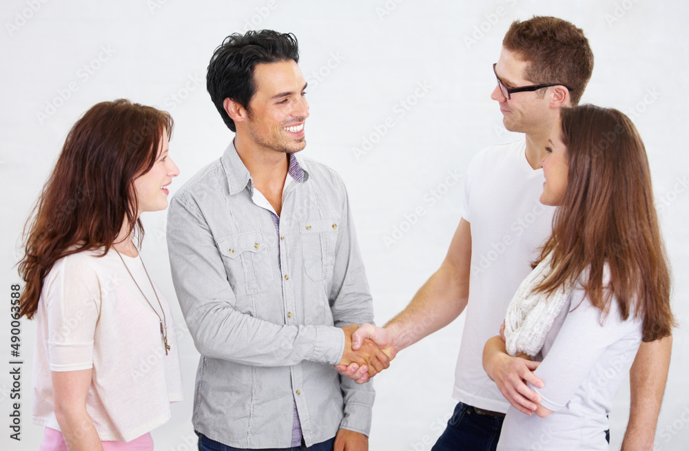 We owe our teams success to you. Shot of a two young business professionals shaking hands while their coworkers look on. We owe our teams success to you. Shot of a two young business professionals shaking hands while their coworkers look on.