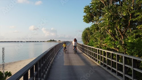 Mother and son riding their bikes on a walkway over the Indian Ocean