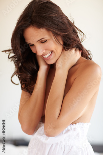 Celebrating femininity. A happy semi-nude woman holding her neck and smiling.