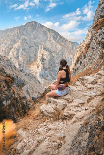 Woman traveler hiking in mountain area sitting on a rock