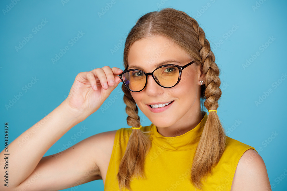 Portrait of a young attractive girl in sunglasses on a blue background