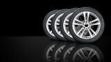 Set of wheels with modern alu rims on black background with mirroring reflection on the floor  - banner composition.