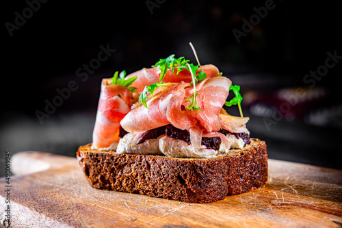 Bruschetta with prosciutto bacon and cream cheese on wooden plate
