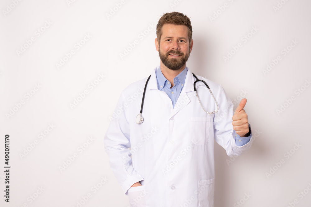 Young smiling male doctor posing with thumb up isolated on white background .