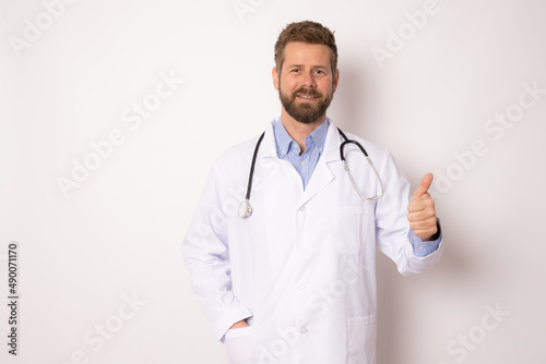 Young smiling male doctor posing with thumb up isolated on white background .
