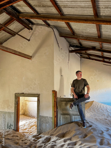 Young man in abandoned building in room. Ghost town Kolmanskop.