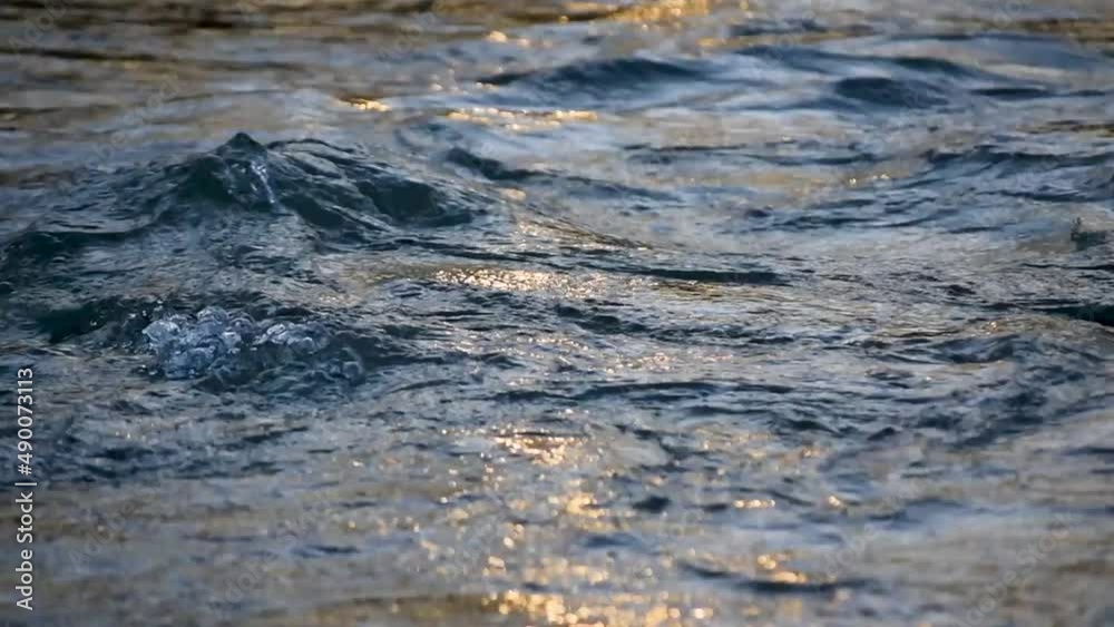 Running water at river with sun flickering on surface Running water at river with sun flickering on surface