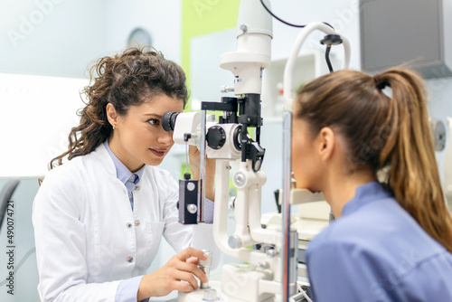 Eye doctor with female patient during an examination in modern clinic. Ophthalmologist is using special medical equipment for eye health saving and improving.