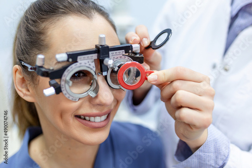 Ophthalmologist examining woman with optometrist trial frame. female patient to check vision in ophthalmological clinic