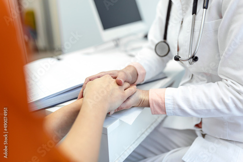 Young female doctor hold hand of caucasian woman patient give comfort  express health care sympathy  medical help trust support encourage reassure infertile patient at medical visit  closeup view.