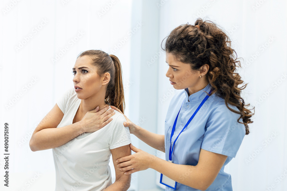 Woman doctor osteopath in medical uniform fixing woman patients shoulder and back joints in manual therapy clinic during visit. Professional osteopath during work with patient concept Woman doctor osteopath in medical uniform fixing woman patients shoulder and back joints in manual therapy clinic during visit. Professional osteopath during work with patient concept