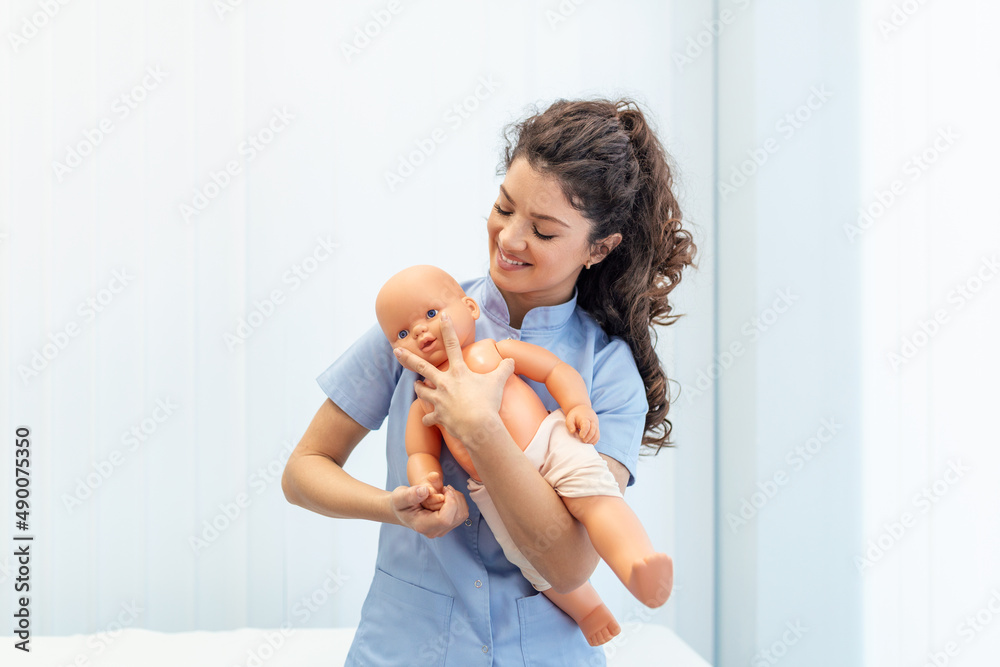 CPR practitioner examining airway passages on infant dummy. Model dummy lays on table and two doctors practice first aid. - obrazy, fototapety, plakaty 