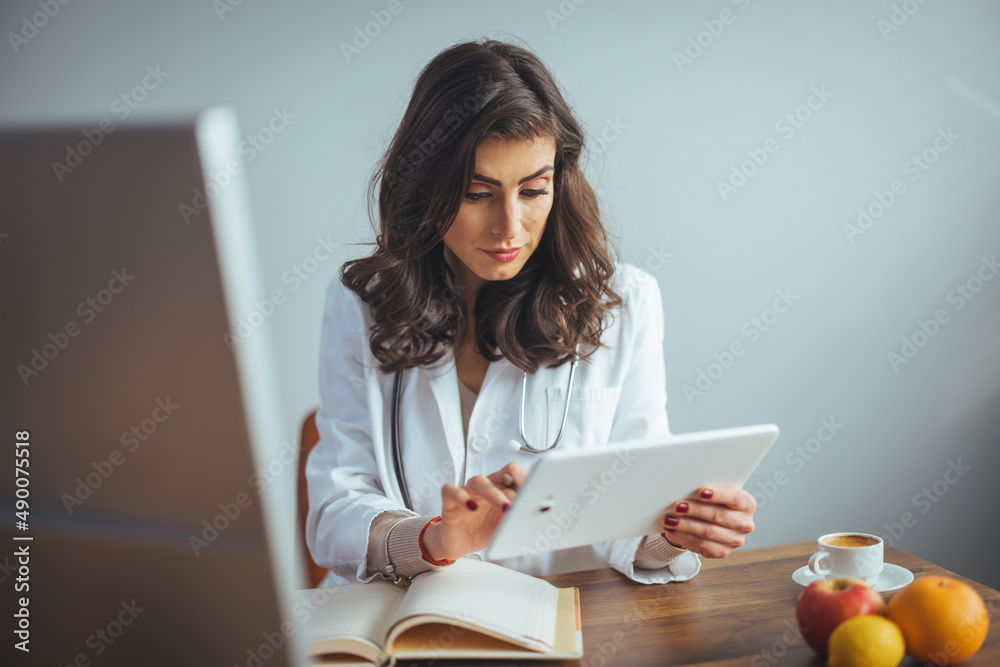 Smiling nutritionist in her office, she is showing healthy vegetables ...