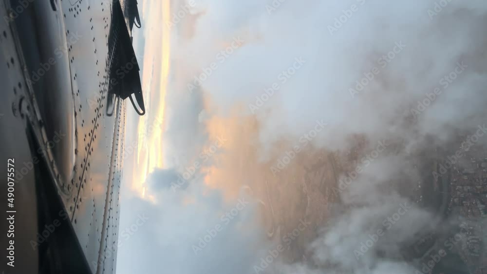 Crossing the clouds with the plane at sunset. Vertical format 4K resolution.