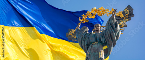 Monument of Independence of Ukraine in front of the Ukrainian flag. The monument is located in the center of Kiev on Independence Square. Russian war in Ukraine. Stop War.