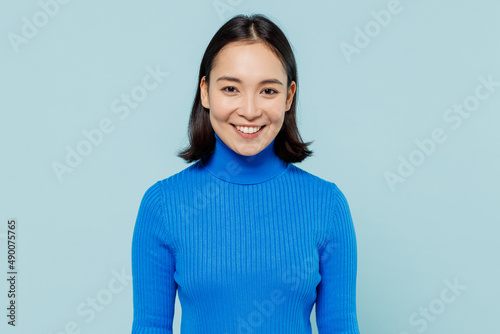 Smiling fancy fascinating young woman of Asian ethnicity 20s years old wear blue shirt looking camera isolated on plain pastel light blue background studio portrait. People emotions lifestyle concept