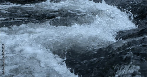 Close-up camera shot of water in slow motion on a river with a few currents.