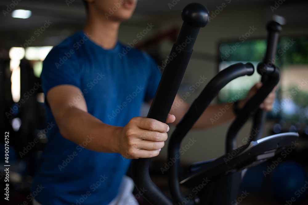 Training gym concept a male teenager doing cardio workout on cycling machine in the gym as his healthy routine Training gym concept a male teenager doing cardio workout on cycling machine in the gym as his healthy routine