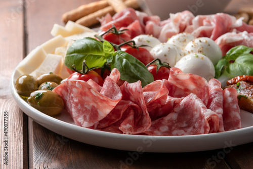 Piatto di tipici cibi italiani, salame, mozzarella, pecorino, prosciutto crudo, pomodoro e basilico photo