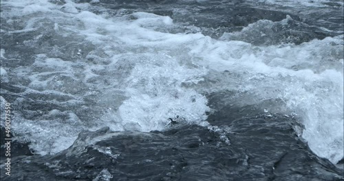 Close-up camera shot of water in slow motion on a river with a few currents.