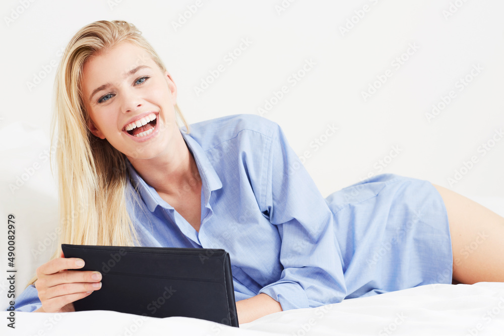 Connect anywhere, any time. A beautiful young blonde woman lying in bed with her digital tablet. Connect anywhere, any time. A beautiful young blonde woman lying in bed with her digital tablet.