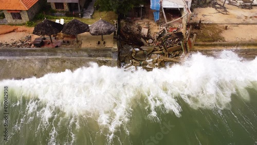 Drone top down shot of destroyed coastline after crashing waves of ocean at night - Environmental catastrophe flooding Vietnam Island photo