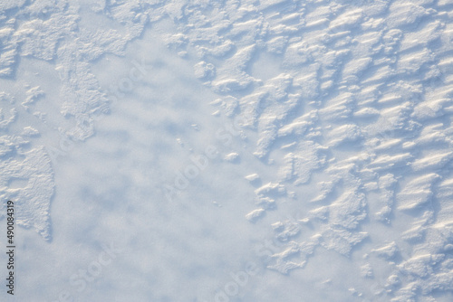 Beautiful winter background with snowy ground. Natural snow texture. Wind sculpted patterns on snow surface.