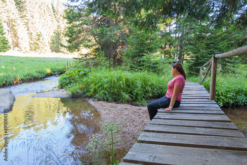 Woman relax by clear water,  mountain forest creek,  on summer day. © mitarart