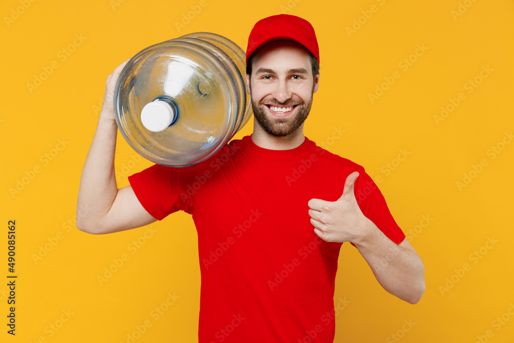 Professional delivery guy employee man in red cap T-shirt uniform workwear work as dealer courier hold water bottle show thumb up isolated on plain yellow background studio portrait. Service concept. Professional delivery guy employee man in red cap T-shirt uniform workwear work as dealer courier hold water bottle show thumb up isolated on plain yellow background studio portrait. Service concept.