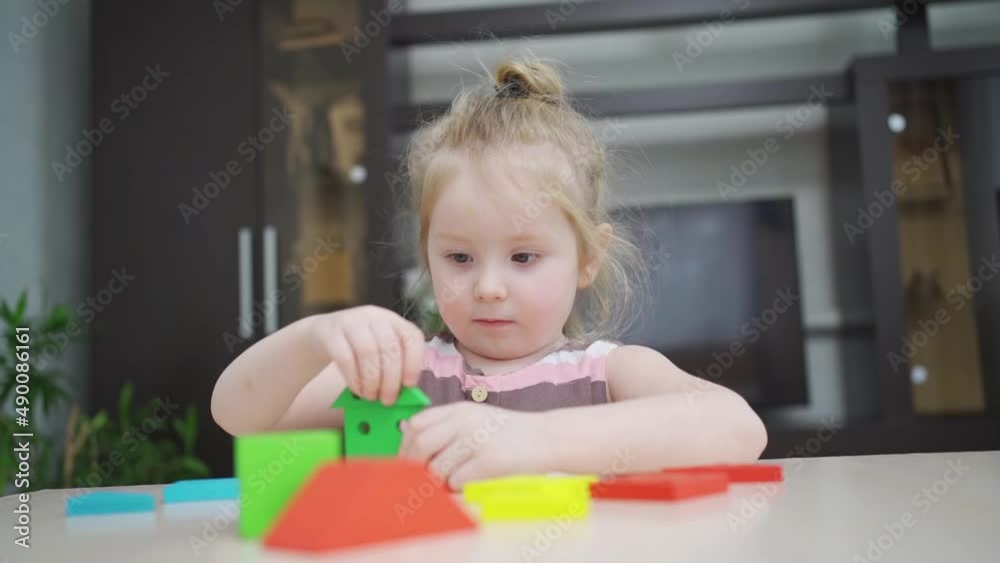 a cute little girl builds houses from a colorful wooden construction set. a cute little girl builds houses from a colorful wooden construction set.